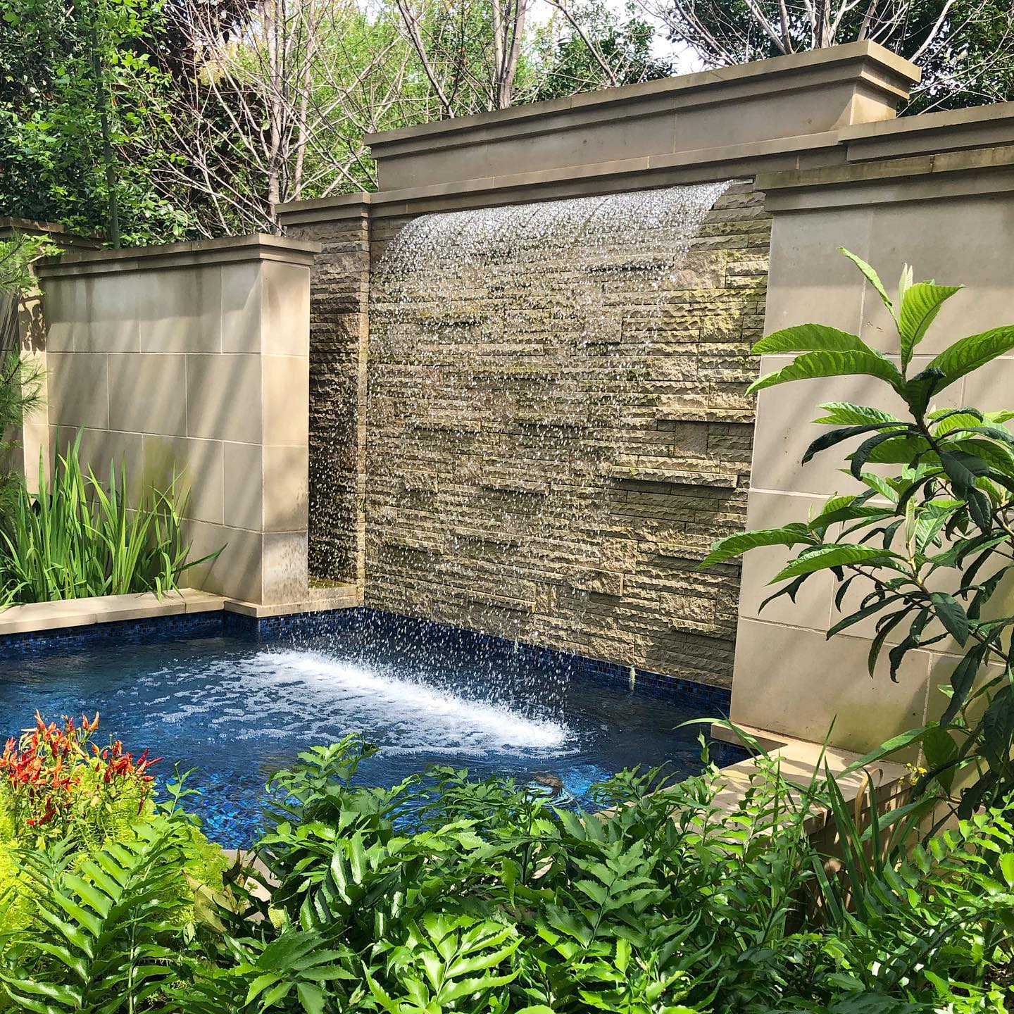 1. Desain Air Terjun Dinding dalam Rumah dengan Lanskap Taman Hijau